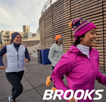 Tre corridori in abbigliamento sportivo: uno con un gilet grigio chiaro, un altro con una maglia a maniche lunghe teal e il terzo con una giacca rosa e un berretto.