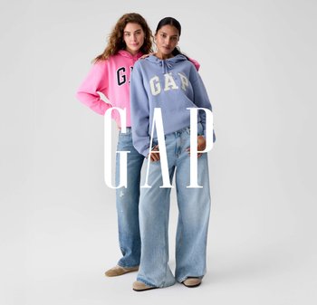 To kvinder iført hættetrøjer: den ene i lyserød med sort skrift og den anden i lyseblå med hvid skrift. Begge bærer vidde jeans.