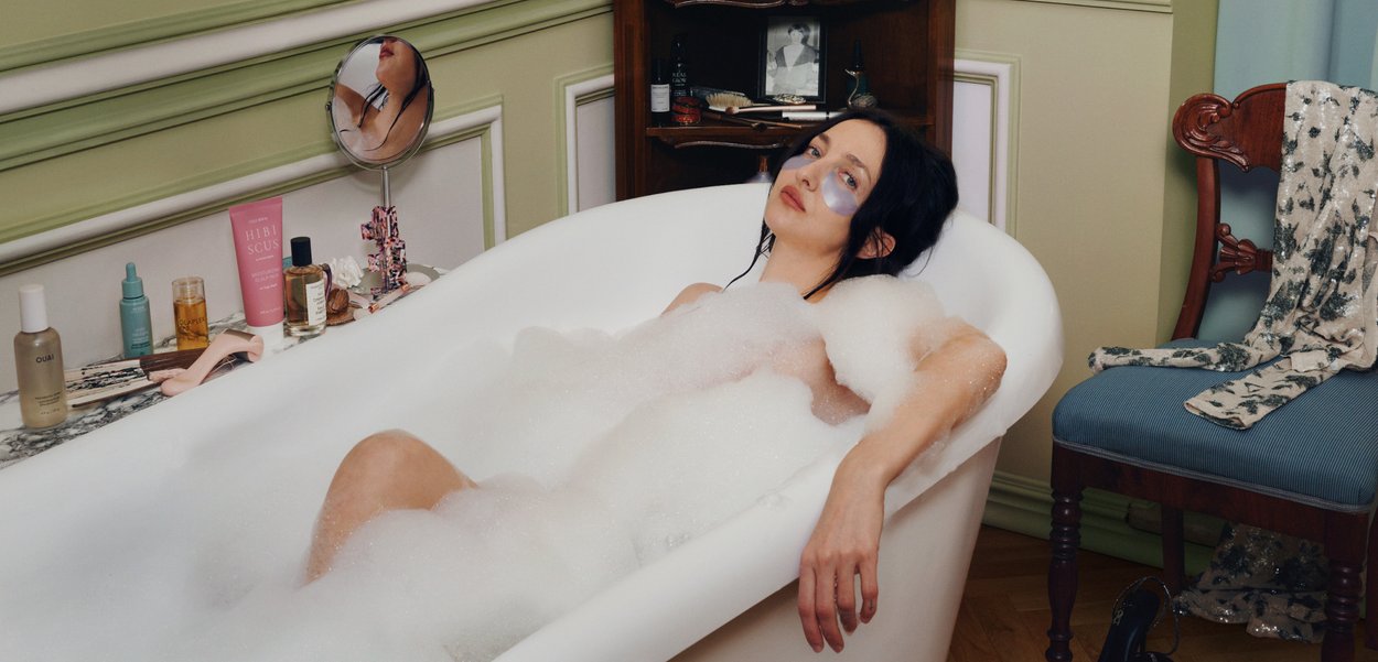 Naine, kellel on silma all plaastrid, lõõgastub mullivannis vanaaegses vannitoas, ümbritsetuna nahahooldustoodetest, toolist, millel on riided ja jalanõud.