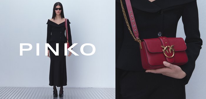Black off-shoulder jacket with buttons, paired with a long black skirt. Holding a small red leather handbag with a gold-accented clasp.