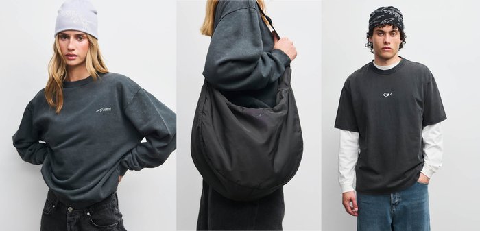 To modeller bærer mørkt afslappet tøj: en kvinde i en mørk sweatshirt og hvid beanie, og en mand i en mørk t-shirt over en hvid langærmet trøje.