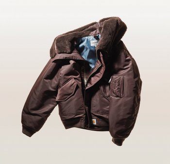 Chaqueta acolchada marrón con cuello de piel sintética, cierre frontal con cremallera, dos grandes bolsillos y puños elásticos. Forrada con material azul claro.