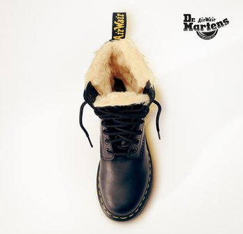 Botte en cuir noir avec un col doublé en polaire, dotée de lacets noirs, de surpiqûres jaunes et d'une languette jaune bouclée pour un enfilage facile.