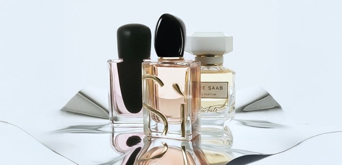 Trois flacons de parfum : un avec un bouchon noir, un corps en verre transparent, au design incurvé ; un autre avec des accents dorés ; et un flacon hexagonal de couleur crème.