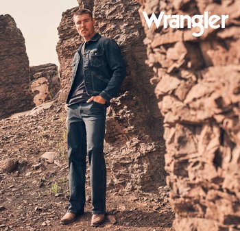 Mørk jeansjakke med brystlommer, svart t-skjorte og mørke jeans. Står på steinete terreng med naturlige teksturer og jordfarger.