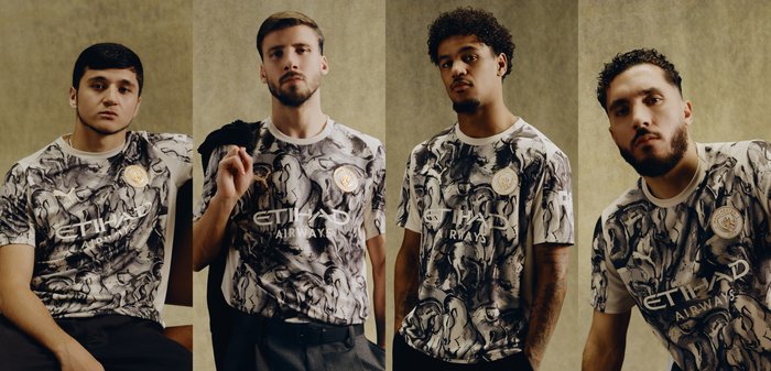 Quatre hommes se tiennent debout ou sont assis devant un fond beige, portant des maillots de football Manchester City assortis noir et blanc marbré avec le logo Etihad Airways.