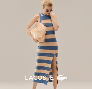 Mujer con vestido sin mangas a rayas azules y beige con abertura lateral, sosteniendo un bolso beige, usando gafas de sol; logotipo de Lacoste en la parte inferior.