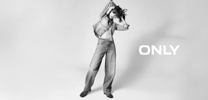 Denimjack en wide-leg jeans in blauw, met een cropped ontwerp. De outfit wordt gecombineerd met zwarte schoeisel. De tekst "ONLY" verschijnt prominent.