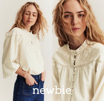 Cream-colored blouse with a ruffled collar, button front, and lace detailing, paired with dark blue denim jeans. Long sleeves and textured fabric.