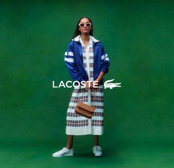 Chaqueta deportiva azul con rayas blancas, vestido estampado, zapatillas blancas y bolso marrón en un sujeto frente a un fondo verde.