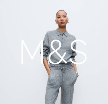 Woman wearing a grey knit sweater with buttons and matching drawstring pants, standing with hands in pockets against a plain background.