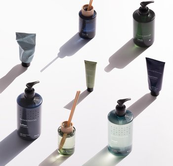 Collection de produits de soin de la peau dans différentes formes et couleurs : bouteilles et tubes bleu foncé et vert avec des designs épurés et des bouchons pompe.