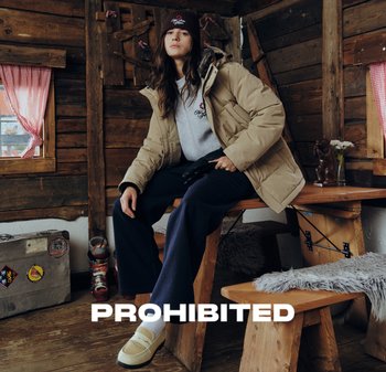 Beige puffer jacket, gray sweatshirt, navy wide-leg pants, knitted brown beanie. Wooden interior with rustic furniture and decorative accents.