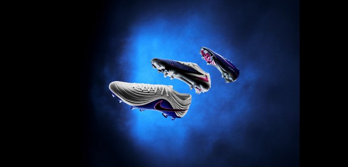 Trois chaussures de football flottantes en blanc, noir et violet avec des accents roses sur un fond bleu fumé.