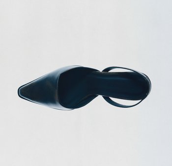 Sorte skinnhøyhælte sko med spiss tå, ankelstroppe og glatt tekstur. Har en formet såle og minimalistisk design.