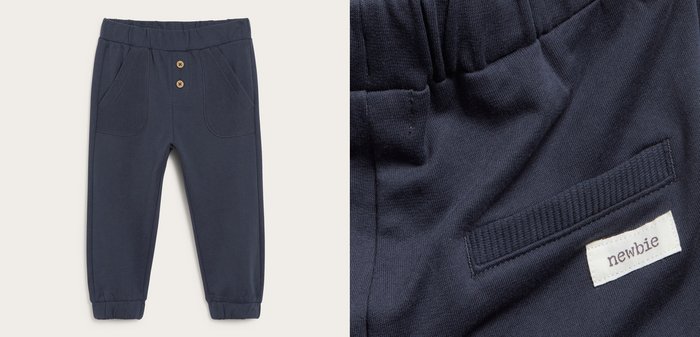 Marineblauwe peutersweatpants met elastische tailleband, geribbelde voorzakken, twee decoratieve houten knopen en elastische manchetten.