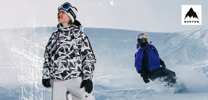 Due snowboarder in abbigliamento invernale su una pista innevata; uno in piedi che guarda verso l'alto, l'altro che intaglia la neve indossando un casco Red Bull.