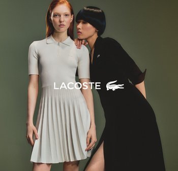 Due modelli indossano abbigliamento Lacoste. Uno indossa un vestito plissettato a coste di un colore crema chiaro; l'altro modella un vestito nero aderente con uno spacco che arriva alla coscia.