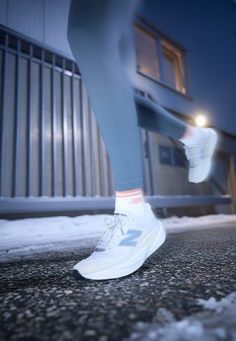 Bele športne strani z belimi in sivimi detajli, mrežasto zgornjščino in oblazinjenim podplatom. Nosijo se s sivimi hlačami in imajo odsevne detajle za boljšo vidnost.