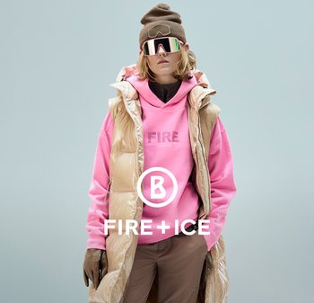 Puchowy beżowy bezrękawnik na różowej bluzie z kapturem z napisem "FIRE" w błyszczących literach. Brązowe spodnie i dziergany brązowy czapka.