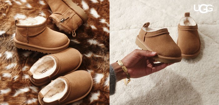 Rjavi semiš UGG copati z belim puhastim podlogom, prikazani na puhastem preprogi in držani z roko, ki nosi zlato zapestnico.