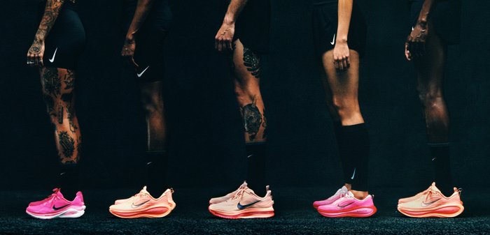 Quattro paia di scarpe da ginnastica Nike in diverse tonalità di rosa, caratterizzate da suole con design e texture contrastanti, indossate sui piedi di alcune persone.