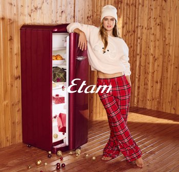 Czerwona lodówka w stylu retro z zaokrąglonymi krawędziami, metaliczną rączką oraz widocznymi owocami w środku. Ciepła drewniana podłoga i ściana z paneli w tle.