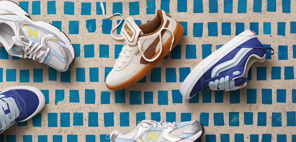 Cinco zapatillas en colores blanco, azul y beige, dispuestas sobre un suelo de baldosas azul y beige.