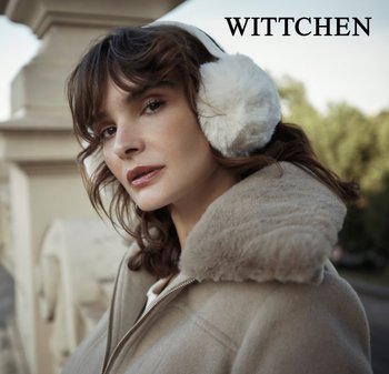 Beżowy płaszcz z futrzanym wykończeniem i wysokim kołnierzem, z białymi futrzanymi nausznikami. Projekt ma gładką teksturę i nowoczesny wygląd.