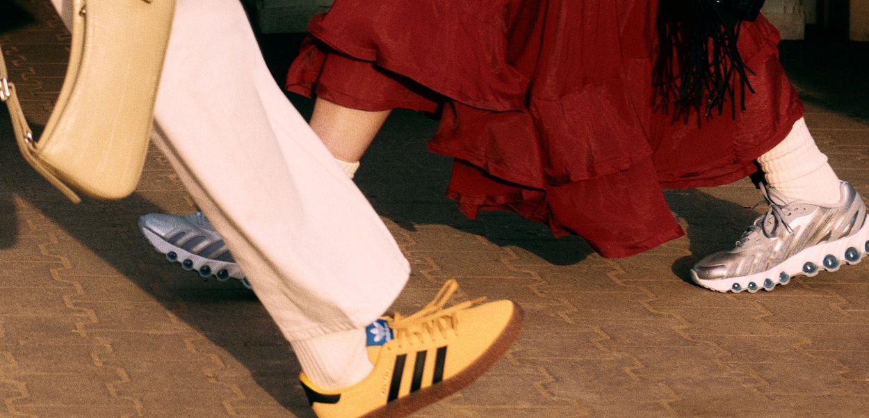 Sneakers: jeden żółty w czarne paski, drugi srebrny z podeszwą przypominającą bąbelki; beżowe skarpetki; zwiewna czerwona spódnica; beżowa torba. Utwardzona powierzchnia.