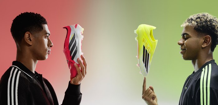 Deux hommes se font face en tenant des chaussures de football : l'un tient une chaussure rouge, l'autre fait tenir une chaussure jaune sur son doigt.