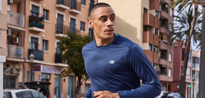 Άνδρας τρέχει έξω φορώντας μπλε μακρυμάνικο μπλουζάκι, με αστικά κτίρια και σταθμευμένα αυτοκίνητα στο φόντο.