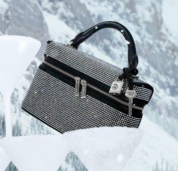 Sort veske dekket med sølvfargede rhinestones, med to glidelåslommer, en dekorativ nøkkelring og et rundet håndtak med stjerneaksenter.