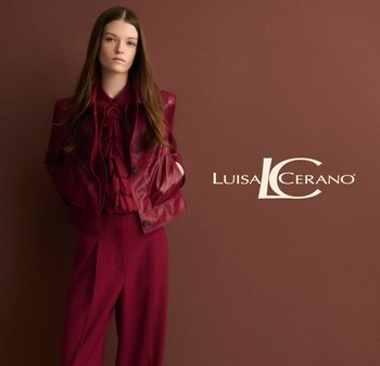 Burgundy leather jacket over a ruffled blouse, paired with tailored pants. Smooth texture and accent buttons on the jacket. Simple background.