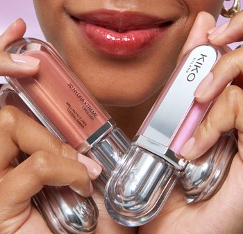 KIKO Milano 3D Hydra Xtreme lip glosses in clear containers with silver accents; one is pink, the other is a shimmery nude, held by hands.