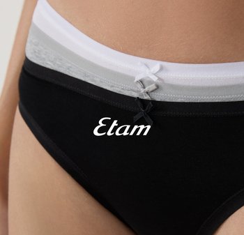 Drie gestapelde katoenen damesonderbroeken in wit, grijs en zwart, elk met een kleine bijpassende strik aan de taille.