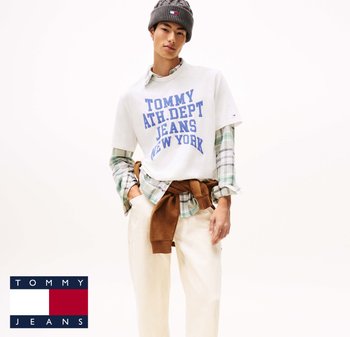 White cotton t-shirt with blue text; green and white plaid shirt layered underneath; beige pants and brown sweater tied at the waist. Gray knit beanie.