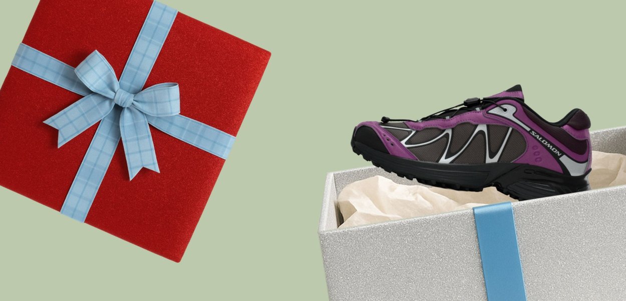 Violetti ja harmaa lenkkarit, joissa on teksturoitu pinta, heijastava kuvio ja mustat yksityiskohdat, esillä hopeisessa laatikossa, jossa sininen nauha.