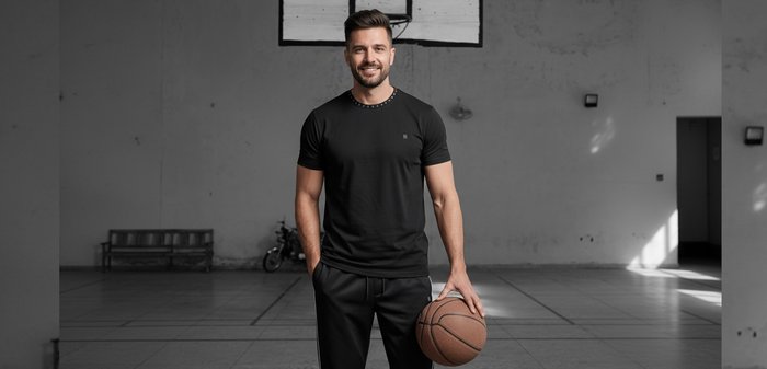 Smiling man in black sportswear holding basketball on indoor court under hoop with "Pier One" text across image.