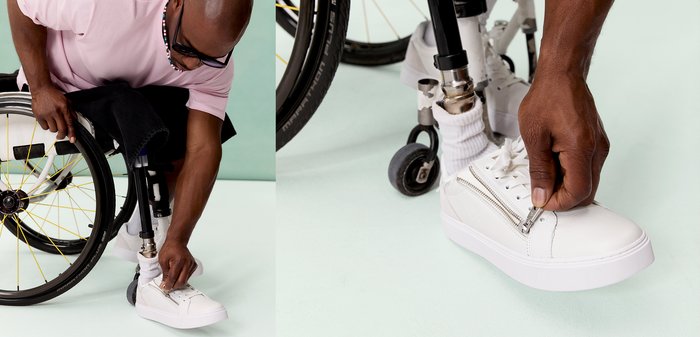 Homme avec une jambe prothétique en fauteuil roulant qui ferme la fermeture éclair d'une chaussure blanche tout en portant une chemise rose et des lunettes.