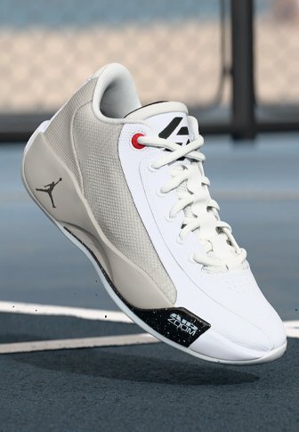 Valged sportlikud jalanõud hallide võrkpaneelide ja nahkpindadega, millel on punased aktsendid ja must kanna detail, ümmargused paelad ning voolujooneline siluett.