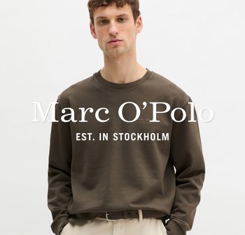 Młody mężczyzna w brązowej bluzie z okrągłym dekoltem i jasnych spodniach, stojący na jednolitym białym tle z logo Marc O’Polo.