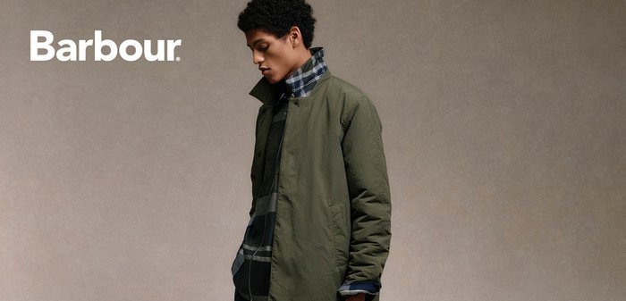 Olivgrüne Außenjacke mit Knopfverschluss, hohem Kragen und Seitentaschen, getragen über einem schwarz-blauen Karoshirt.