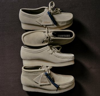Chaussures en daim beige empilées, avec un bout rond, des laçages et une semelle texturée. Accent bleu notable et étiquette de marque visibles.