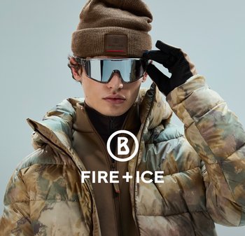 Beżowa kurtka puchowa w wzór kamuflażu, nałożona na brązową warstwę pośrednią. Posiada lustrzane okulary przeciwsłoneczne i brązową dzianinową czapkę. Czarne rękawice.