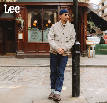 Ljusgrå jacka i ullblandning med fickor framtill, knappstängning och en beige stickad krage; kombinerad med mörkblå jeans och bruna stövlar.