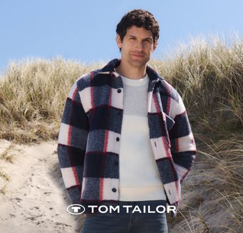 Kariertes Fleece-Jacket in Marineblau, Weiß und Rot. Mit Knopfverschluss, spitzem Kragen und zwei Brusttaschen. Über einem leichten Strickpullover getragen.