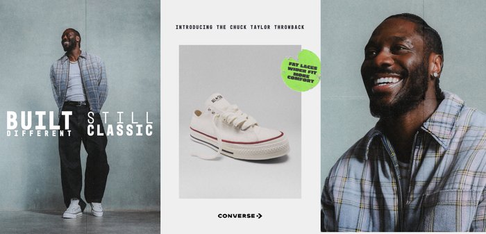 Le rappeur britannique Knucks est assis sur un canapé en cuir noir, portant une tenue noire et des baskets blanches Chuck Taylor avec des lacets larges.