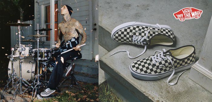 Tetovaný bubeník s čiapkou a kopačkami Vans na kocky hrá na bicie vonku pri dome, okolo neho padajú listy.