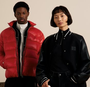 Un jeune homme en doudoune rouge et en chemise blanche à boutons se tient à côté d'une femme en veste de varsity noire avec des manches en cuir.